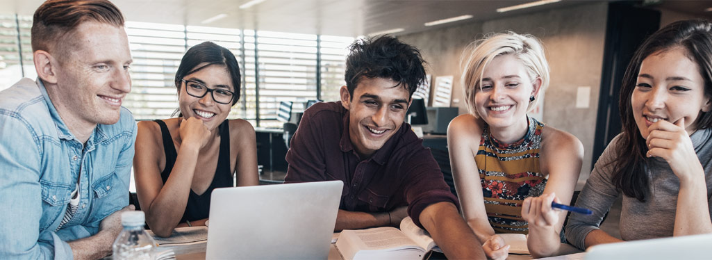 Eine Gruppe Studierender arbeitet gemeinsam an einem Tisch mit Laptops und Notizblöcken.