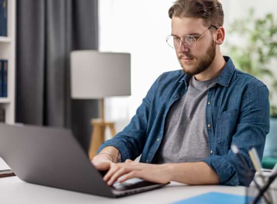 Ein Mann mit Brille sitzt konzentriert vor seinem Laptop.