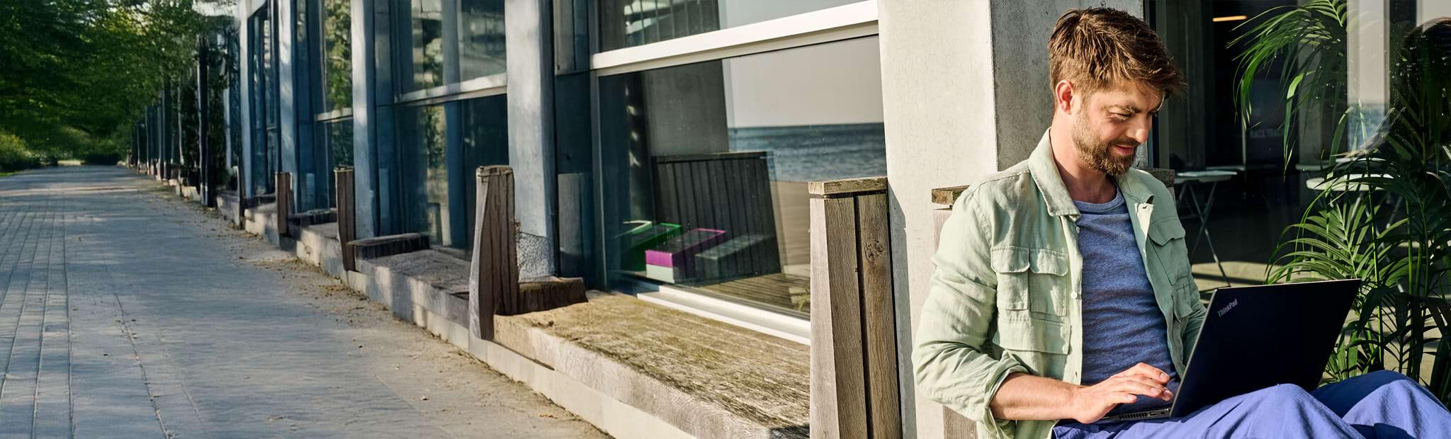 Ein Mann wird von der Seite gezeigt. Er sitzt draußen und scheint konzentriert an einem Laptop zu arbeiten. 